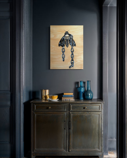 Dark gray wall with a wooden cabinet and decorative items, including a painting of a moth.